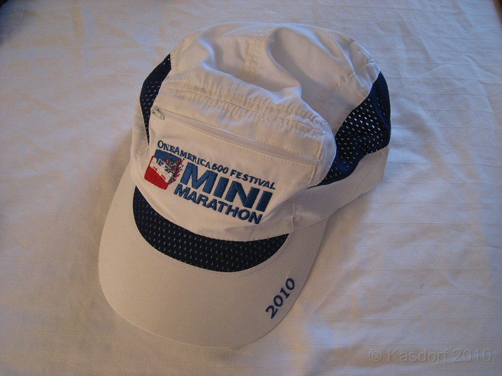 Indy Mini-Marathon 2010 055.jpg - Checking out all the swag back in the hotel room A nice running hat. Even has a little zippered pocket to put things in... seems like a headache waiting to happen. But maybe a car key would be okay... until the hat blows off and you have to stop the race to chase it down so you can get back in your car when you are done.
